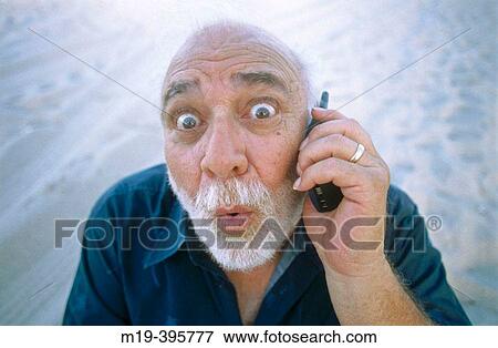 Stock Photo - man with funny face/big eyes on cell phone. Fotosearch