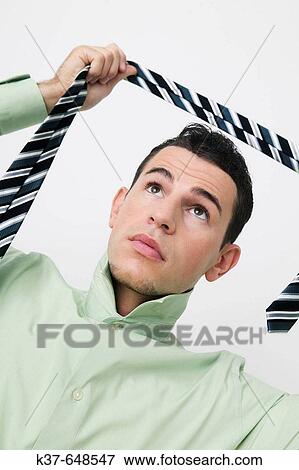 Stock Photo - Man with his collar up & about to put on his tie. Fotosearch