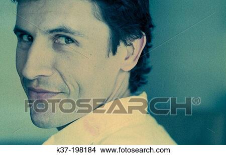 Picture - Man with knowing expression looking over his shoulder. Fotosearch