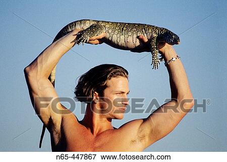 Stock Photo - Man with Monitor Lizard. Fotosearch