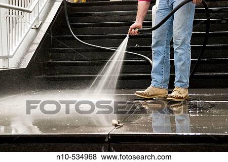 Man, with only his legs visible, using a hose to wash the ledge in front of an office building View Large Photo Image Stock Photo - Man, with only his legs visible, using a hose to wash the ledge in front of an office building. Fotosearch