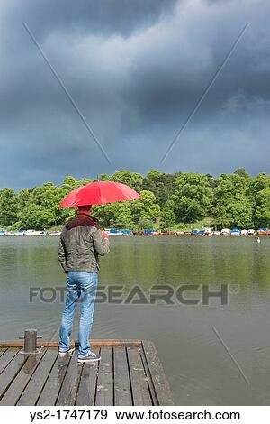 Man with umbrella looking at rainclouds in Stockholm, Sweden View Large Photo Image Stock Photo - Man with umbrella looking at rainclouds in Stockholm, Sweden. Fotosearch