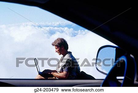 Man working on laptop computer above clouds, view through car window View Large Photo Image Stock Photo - Man working on laptop computer above clouds, view through car window. Fotosearch