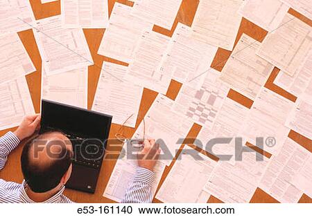 Stock Image - Man working on taxes. Fotosearch