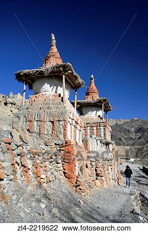 Stock Image - Mani wall (stones inscribed with a buddhist mantra) and stupa (chorten) in the village of Tangge. Nepal, Gandaki, Upper Mustang (near the border with Tibet). Model Released.. Fotosearch