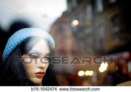 mannequin-faced woman in the foreground behind a store window with reflections in the glass View Large Photo Image Picture - mannequin-faced woman in the foreground behind a store window with reflections in the glass. Fotosearch
