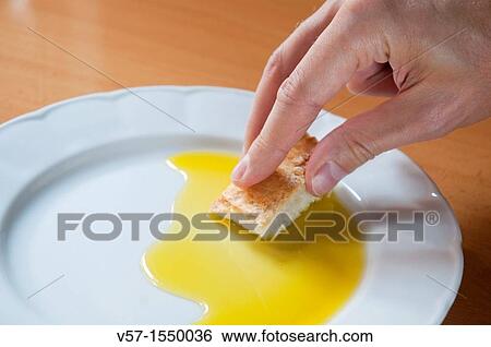 Man's hand dipping bread in olive oil. Close view. View Large Photo Image Stock Photograph - Man's hand dipping bread in olive oil. Close view.. Fotosearch