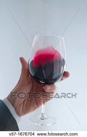 Man's hand holding a glass of red wine, tasting it View Large Photo Image Picture - Man's hand holding a glass of red wine, tasting it. Fotosearch