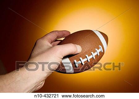 Man's hand holding a small football View Large Photo Image Stock Image - Man's hand holding a small football. Fotosearch