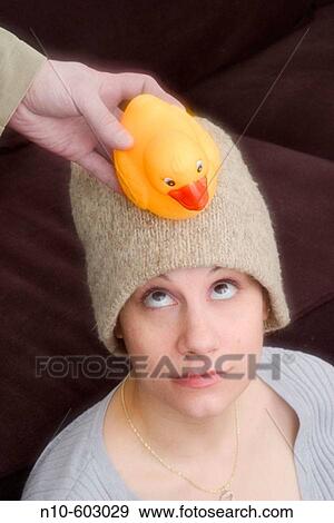 Man's hand holding a yellow rubber duck next to a young woman's head. View Large Photo Image Stock Photo - Man's hand holding a yellow rubber duck next to a young woman's head.. Fotosearch