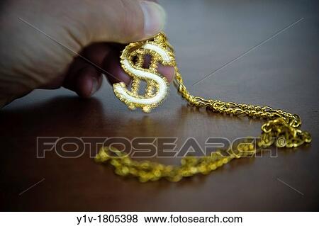 Stock Photo - Man's hand holding an American dollar-sign necklace. Fotosearch