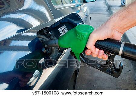 Stock Photo - Man's hand holding gas pistol, refuelling at a gas station. Close view.. Fotosearch