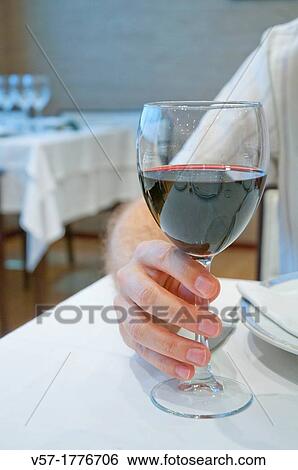 Man's hand with a glass of red wine in a restaurant. Close view. View Large Photo Image Stock Photograph - Man's hand with a glass of red wine in a restaurant. Close view.. Fotosearch