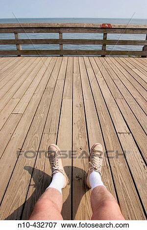 Man's outstretched legs and feet, in white socks and dirty sneakers, resting on the boardwalk at the beach View Large Photo Image Stock Photo - Man's outstretched legs and feet, in white socks and dirty sneakers, resting on the boardwalk at the beach. Fotosearch