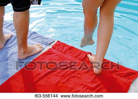 man/woman standing at edge of pool- woman dipping foot into water View Large Photo Image Picture - man/woman standing at edge of pool- woman dipping foot into water. Fotosearch
