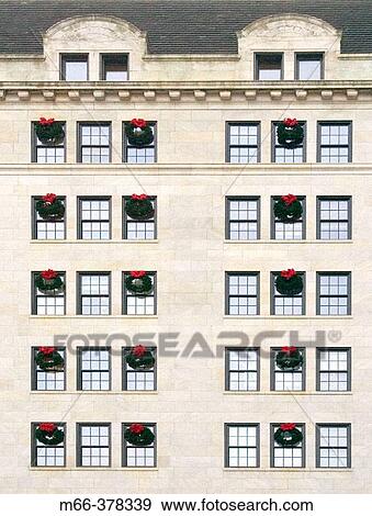 Many Christmas wreaths hanging from rows of windows on several floors of a white stone city building in New York City. View Large Photo Image Stock Photo - Many Christmas wreaths hanging from rows of windows on several floors of a white stone city building in New York City.. Fotosearch