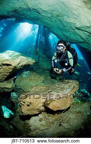 Stock Image - Mario, a cavern/cave guide with Dive Adventuras, dives near the stricking sunlight rays visible during a dive in Chac Mool (God of Rain) Cenote, Riviera Maya, Mexico. Fotosearch