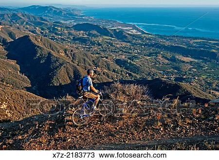 Stock Image - Mark Weber mountain biking the Romero Road Trail high above the Pacific Ocean and the city of Santa Barbara in the Santa Ynez Mountains in southern California.. Fotosearch
