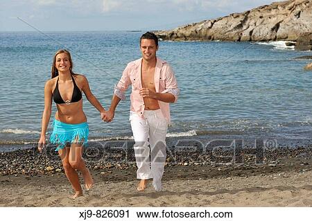 Stock Image - Married couple running on beach. Fotosearch