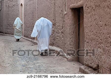 Stock Photograph - Married women in traditional clothing walking on the streets of a Ksar, Figuig oasis, Morocco.. Fotosearch