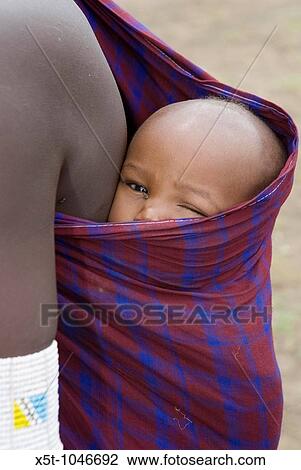Masai mother carrying child on her back, in the forest the Ngorongoro Conservation Area or NCA is a conservation area situated 180 km west of Arusha in the Crater Highlands area of Tanzania View Large Photo Image Stock Image - Masai mother carrying child on her back, in the forest the Ngorongoro Conservation Area or NCA is a conservation area situated 180 km west of Arusha in the Crater Highlands area of Tanzania. Fotosearch