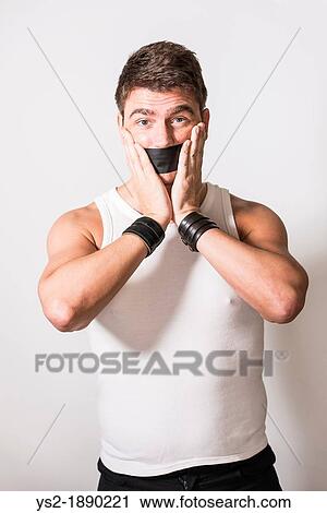 Stock Image - Masculine adult male silenced with black tape over mouth. Fotosearch