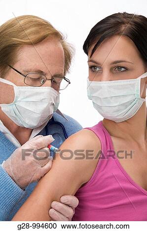 masked doctor vaccinating or giving an injection to a masked young woman patient View Large Photo Image Stock Image - masked doctor vaccinating or giving an injection to a masked young woman patient. Fotosearch