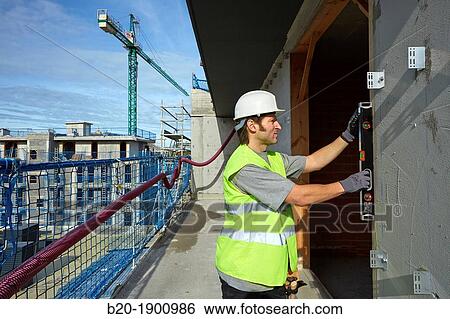 Stock Photograph - Mason checking the level of a wall, Bricklayer with personal protective equipment, PPE, Apartment Building under construction, Donostia, San Sebastian, Gipuzkoa, Basque Country, Spain. Fotosearch