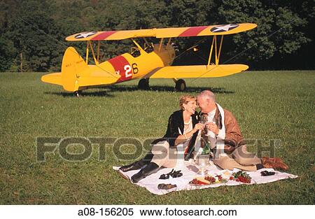 Mature couple having picnic beside airplane View Large Photo Image Stock Photography - Mature couple having picnic beside airplane. Fotosearch