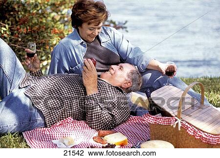 Stock Image - Mature couple on a picnic by the lake. Fotosearch