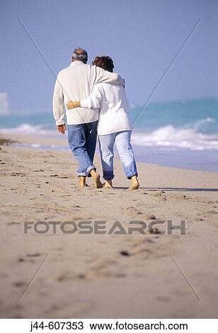 Mature couple walking at the beach wearing cloths View Large Photo Image Stock Image - Mature couple walking at the beach wearing cloths. Fotosearch