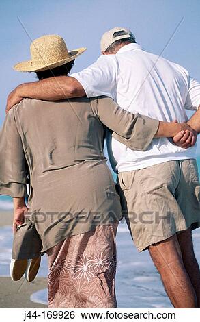 Stock Photograph - Mature couple walking at the beach. Fotosearch
