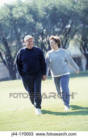 Stock Image - Mature couple walking outdoors in sportswear, Florida. Fotosearch