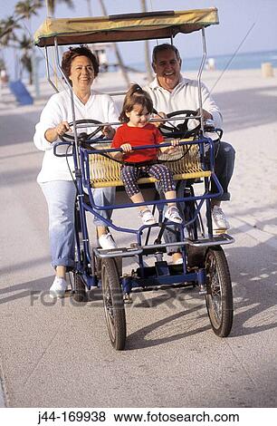 Mature couple with granddaughter riding a four wheel bike at the beach View Large Photo Image Stock Photo - Mature couple with granddaughter riding a four wheel bike at the beach. Fotosearch