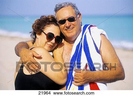 Mature couple with sunglasses and towel at the beach View Large Photo Image Picture - Mature couple with sunglasses and towel at the beach. Fotosearch
