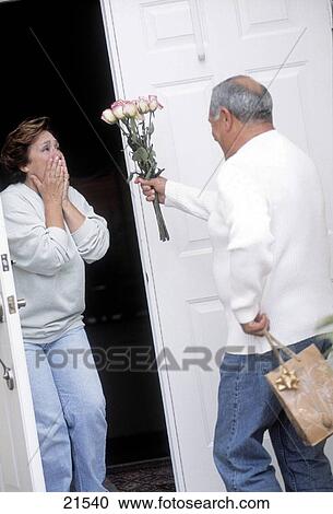 Stock Image - Mature man bringing flowers to woman. Fotosearch