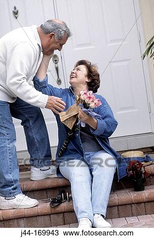Mature man giving flowers to a mature woman in front of the house View Large Photo Image Stock Image - Mature man giving flowers to a mature woman in front of the house. Fotosearch