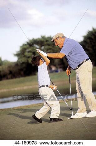 Mature man with grandson celebrating while playing golf View Large Photo Image Stock Photo - Mature man with grandson celebrating while playing golf. Fotosearch