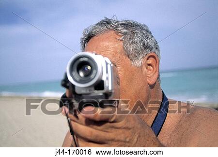 Mature man with video camera at the beach, Florida, USA View Large Photo Image Stock Photograph - Mature man with video camera at the beach, Florida, USA. Fotosearch
