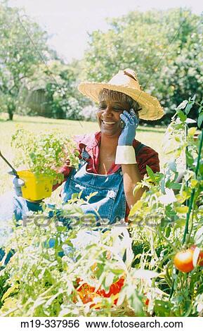Stock Photograph - mature woman in her garden on cellular. Fotosearch