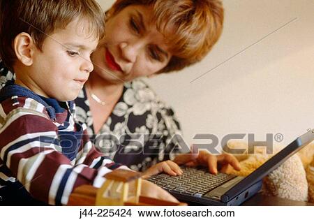 Mature woman showing infant boy laptop computer View Large Photo Image Picture - Mature woman showing infant boy laptop computer. Fotosearch