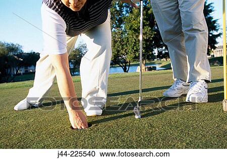 Mature woman taking out golf ball from hole View Large Photo Image Stock Image - Mature woman taking out golf ball from hole. Fotosearch