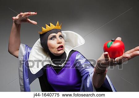 Mature woman wearing the evil queen costume holding a plastic apple View Large Photo Image Stock Photography - Mature woman wearing the evil queen costume holding a plastic apple. Fotosearch