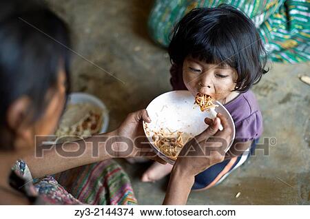 Picture - Maya children is fed in Aqua Escondida, Solola, Guatemala.. Fotosearch