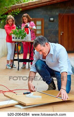 Picture - Measuring a wooden board. Tinkering. Father and children doing DIY.. Fotosearch