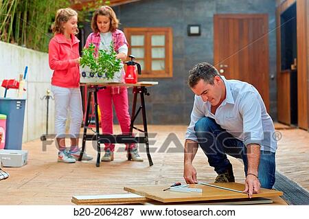 Measuring a wooden board. Tinkering. Father and children doing DIY. View Large Photo Image Stock Photo - Measuring a wooden board. Tinkering. Father and children doing DIY.. Fotosearch
