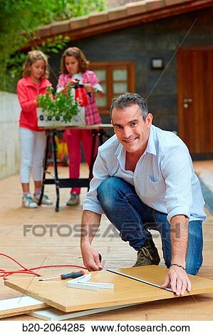 Measuring a wooden board. Tinkering. Father and children doing DIY. View Large Photo Image Stock Photography - Measuring a wooden board. Tinkering. Father and children doing DIY.. Fotosearch