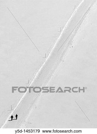 Stock Photo - Men on an empty snow track, Swiss Alps. Fotosearch