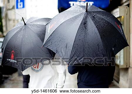 men with big, black, wet umbrellas on a street during heavy rain, Geneva, Switzerland View Large Photo Image Stock Photograph - men with big, black, wet umbrellas on a street during heavy rain, Geneva, Switzerland. Fotosearch
