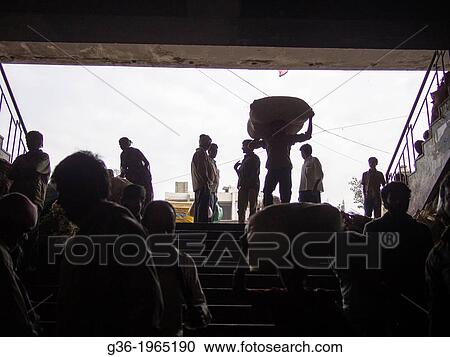Stock Image - Men's silhouettes reveal their conversation and labor against a bright sky in Bangalore, Karnataka, India.. Fotosearch